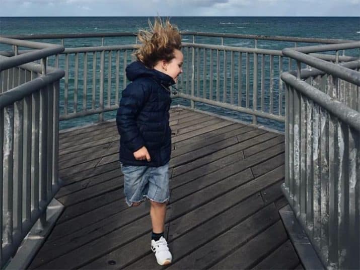 young boy running down a jetty